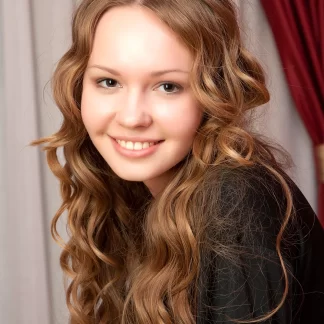 Обаятельная милашка c волнистыми волосами сексуально позирует на постели